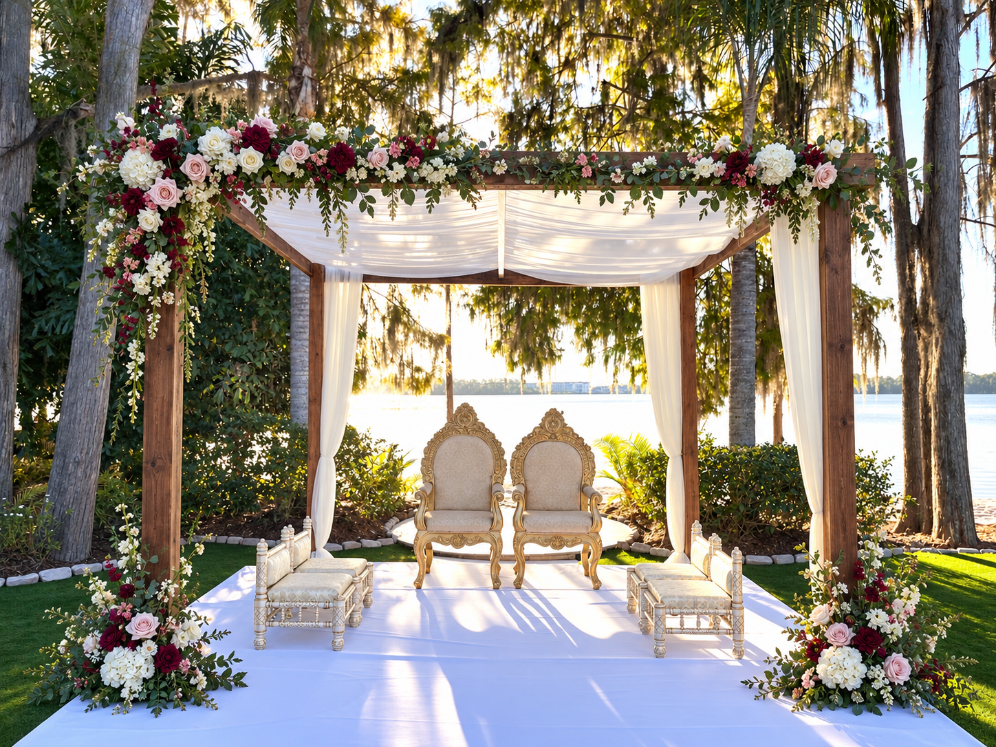 Dark-wood lakeside mandap with a floral garland across the top
